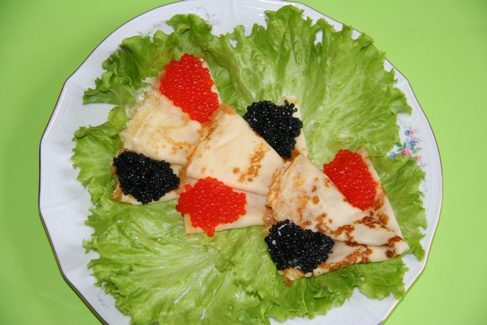 Pancakes with red and black caviar on lettuce