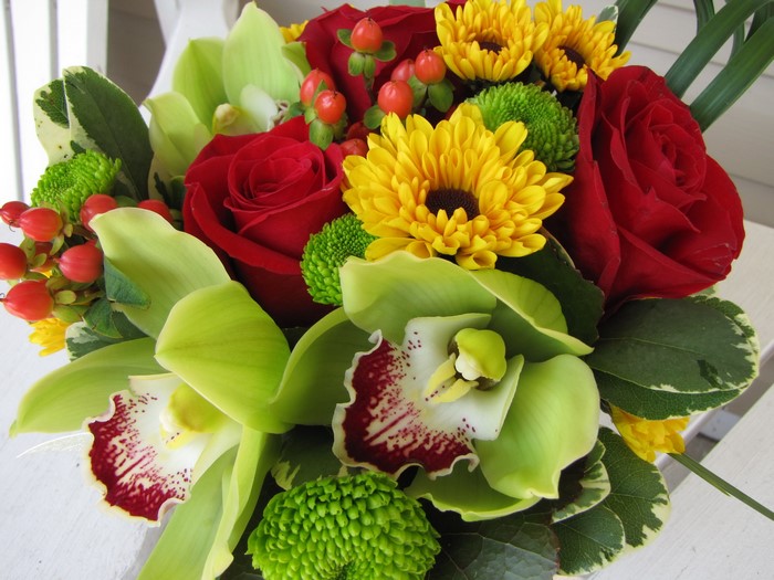 Bouquet of red roses, yellow daisies, and green orchids