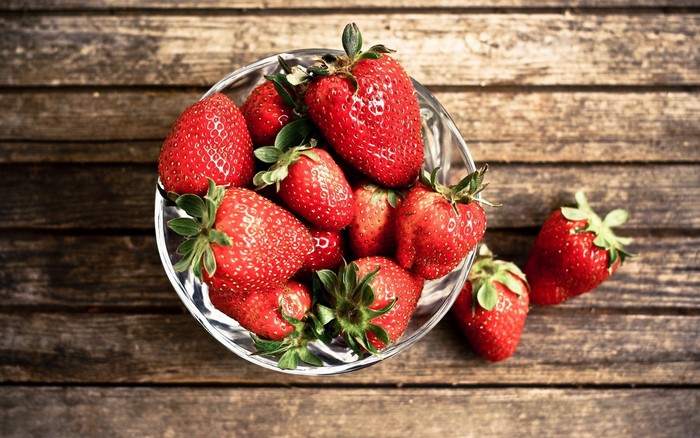 Strawberries in a bowl on wooden planks