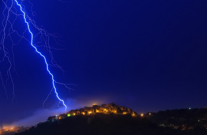Lightning strikes over a village at night