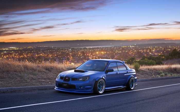 Blue Subaru Impreza WRX STI on a hill at sunset
