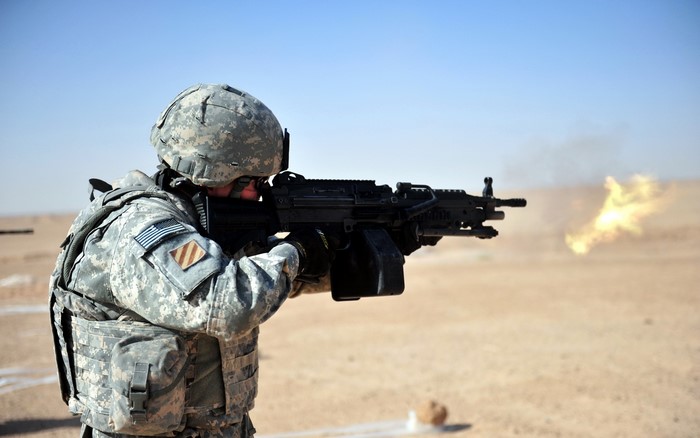 Soldier firing a machine gun in a desert