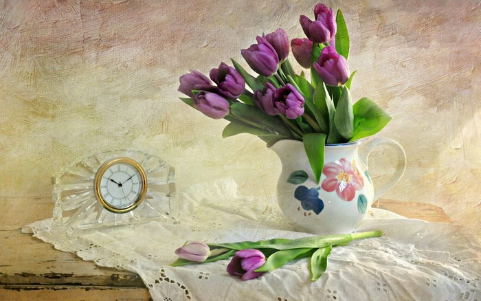 Purple tulips in a jug next to a clock