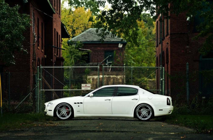White Maserati Quattroporte parked by abandoned buildings