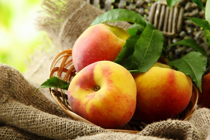Peaches in a basket with leaves