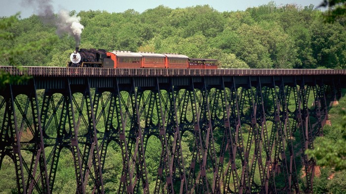 Steam train crossing a tall iron bridge