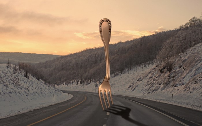 Giant fork on a snowy road at sunset