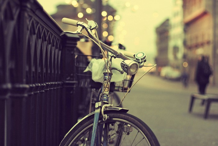 Bicycle parked by a fence on a street