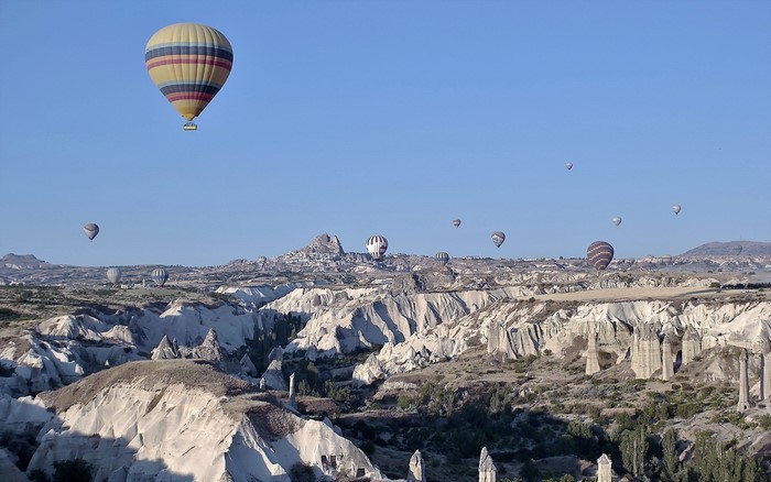 Hot air balloons flying over a rocky canyon landscape