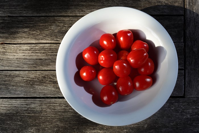 Tomatoes in a white bowl on wood planks