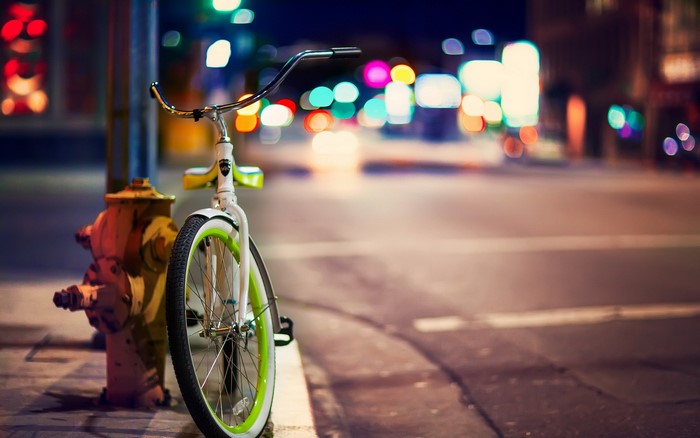 Bicycle parked next to a fire hydrant at night