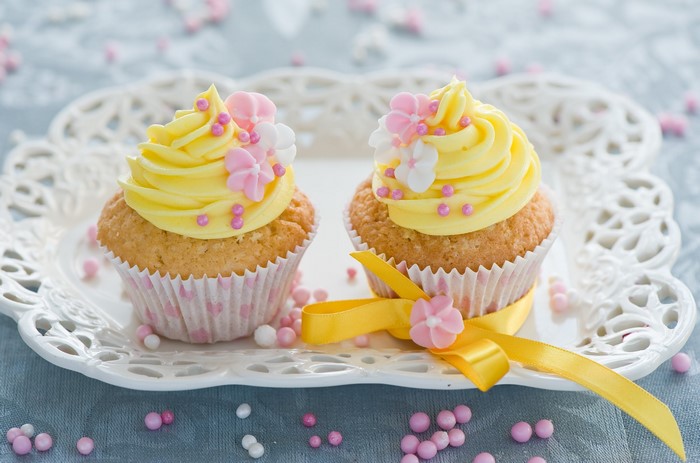 Two yellow cupcakes with pink and white flowers