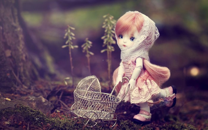 Doll with a baby carriage in a forest