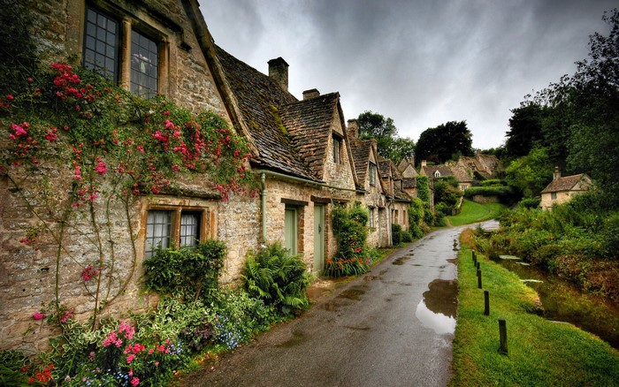 Old stone houses with roses along a wet road