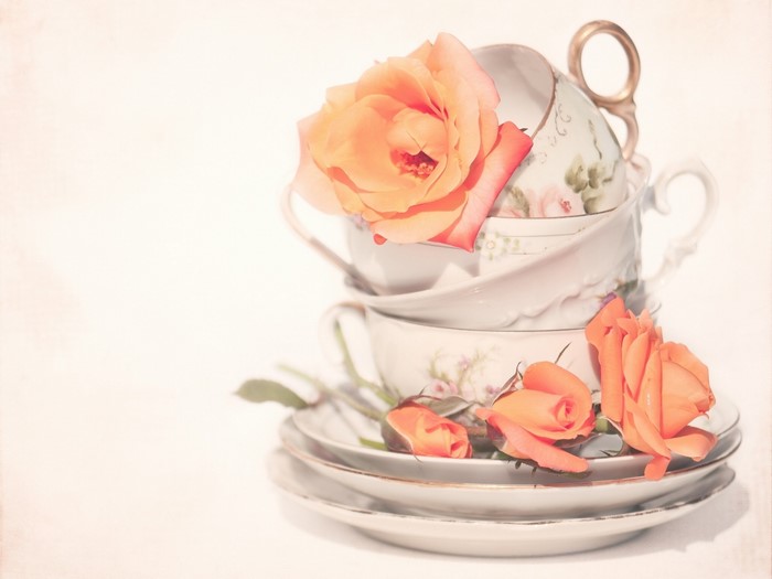 Stack of teacups with orange roses and saucers