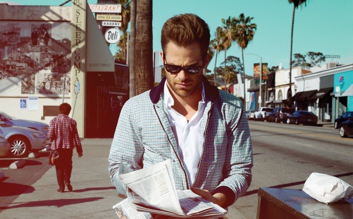 Chris Pine reading a newspaper on a street