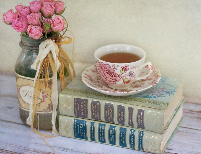 Pink roses in a jar with a teacup and books