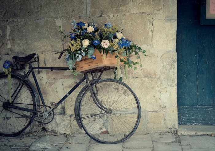 Old bicycle with flowers against a stone wall