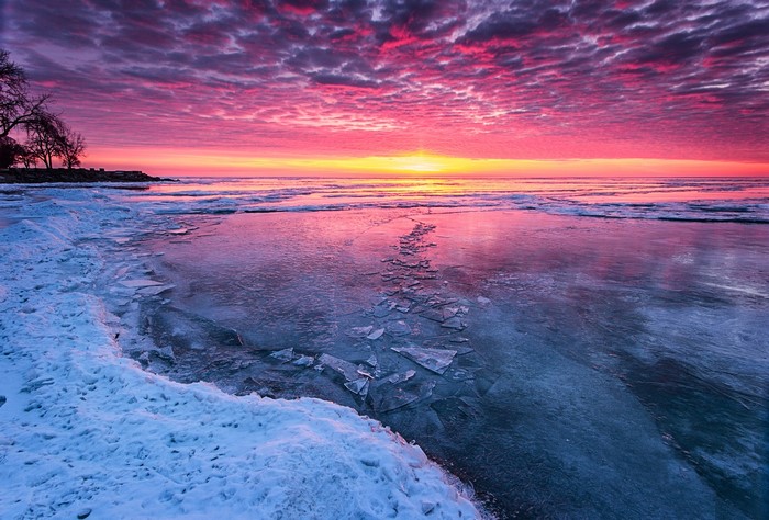 Frozen lake at sunrise with pink clouds