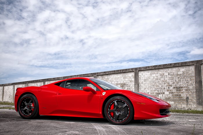Red Ferrari 458 Italia parked near a brick wall