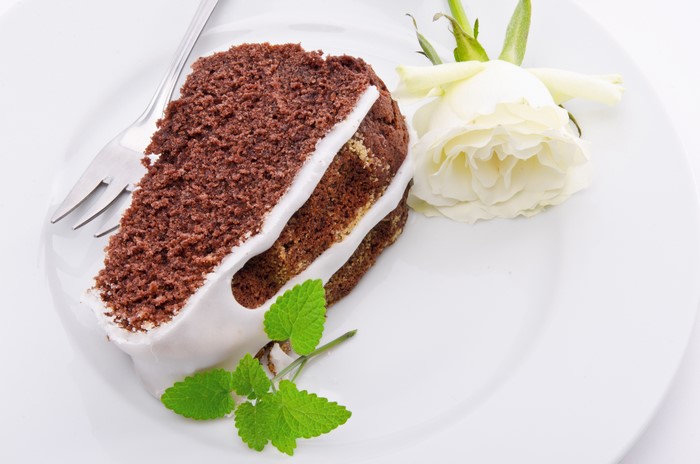 Chocolate cake slice with white rose and mint