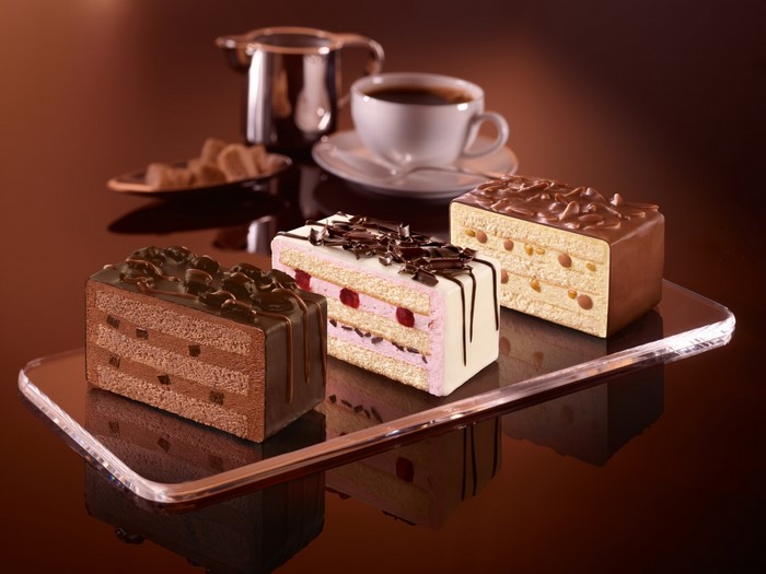 Three slices of cake with coffee and sugar cubes