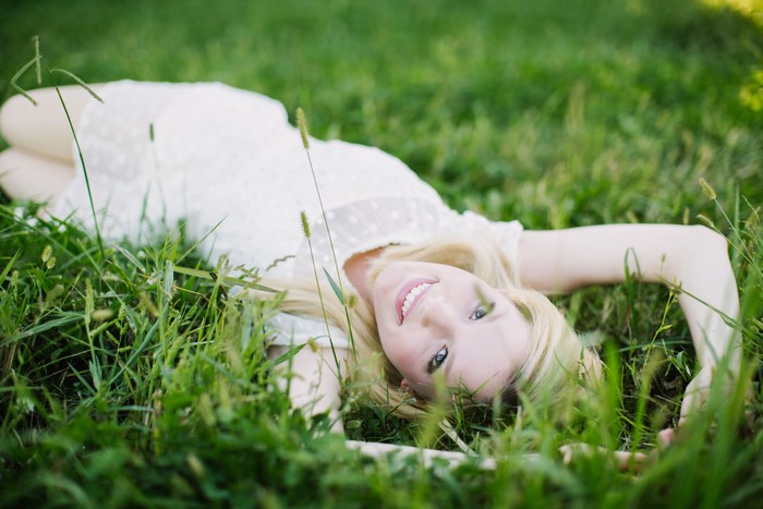 Blonde girl in white dress lying on grass