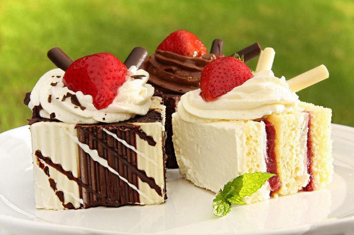Three slices of cake with strawberries and cream