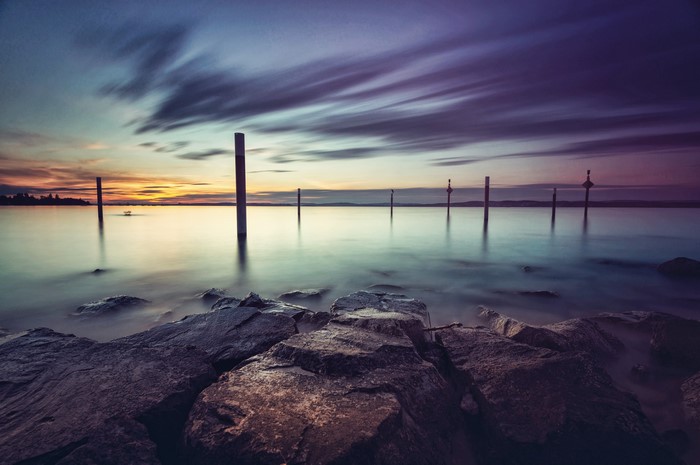 Sunset over a rocky lake with posts