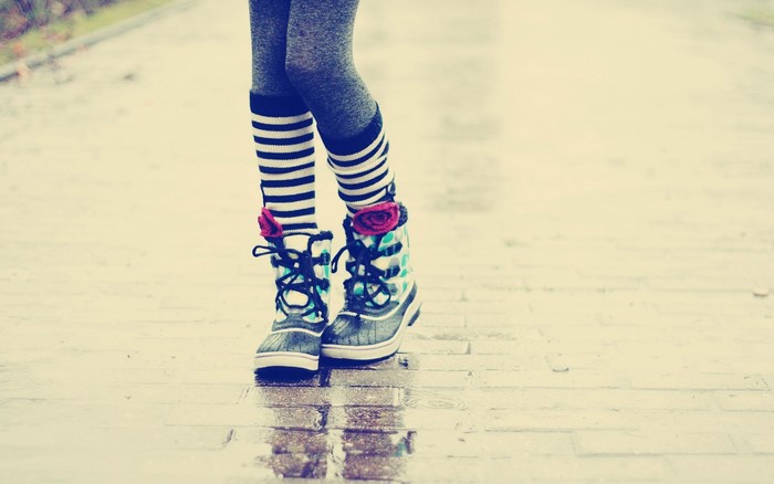 Legs in striped socks and patterned boots on wet pavement