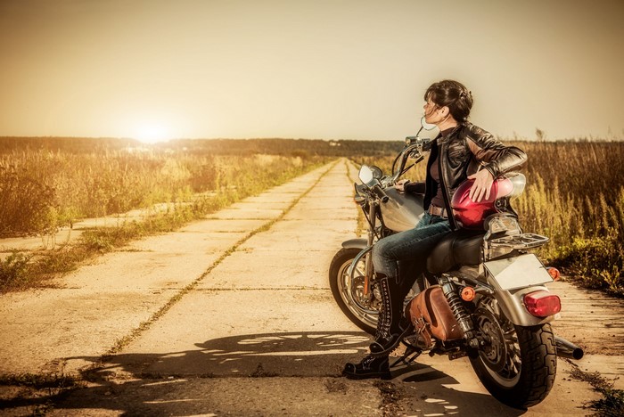 Woman in leather jacket on a motorcycle on a road
