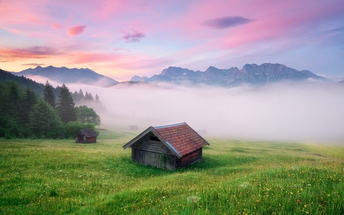 Wooden huts in foggy Bavarian Alps at sunrise
