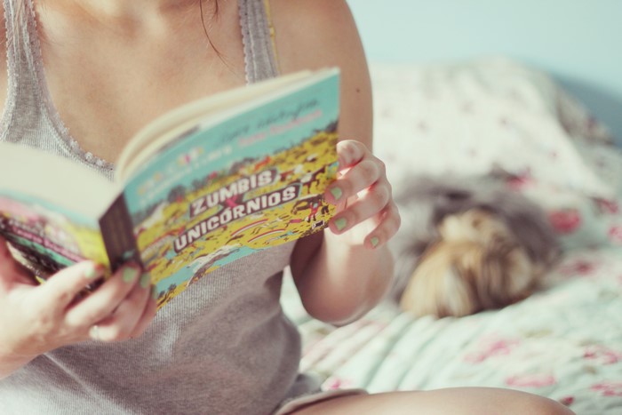 Person reading a book titled Zumbis e Unicórnios