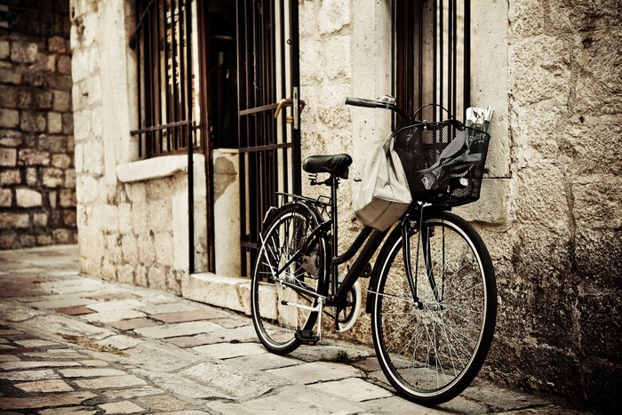 Bicycle parked on a cobblestone street next to a stone building