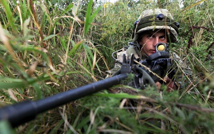 Soldier aiming a rifle in tall grass