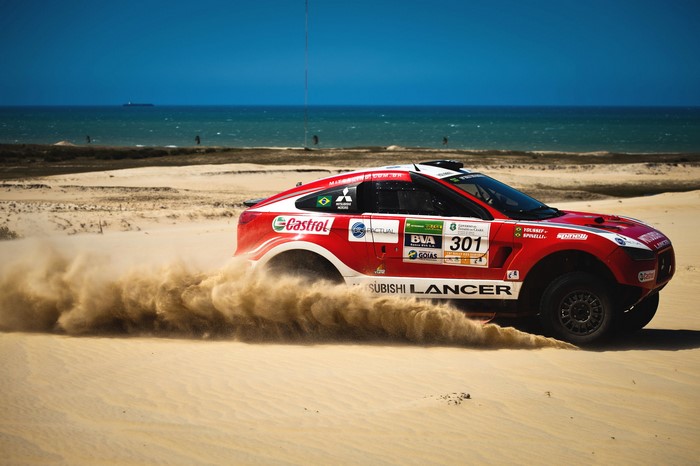 Red Mitsubishi Lancer rally car on a sandy beach