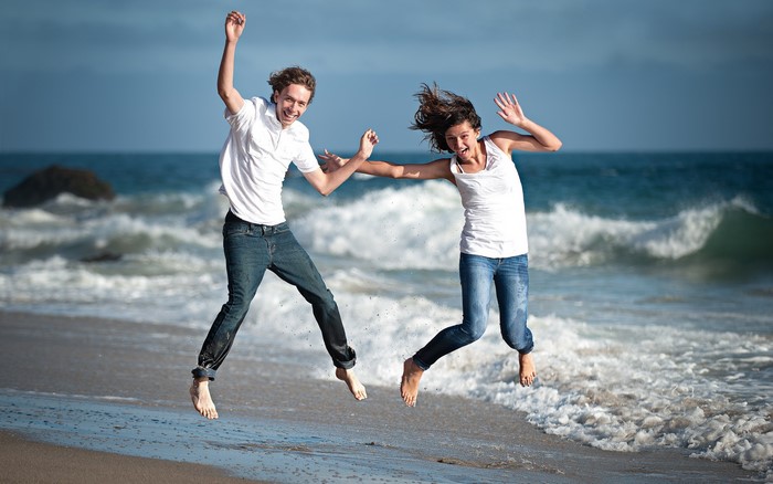 Couple jumping on a beach with waves