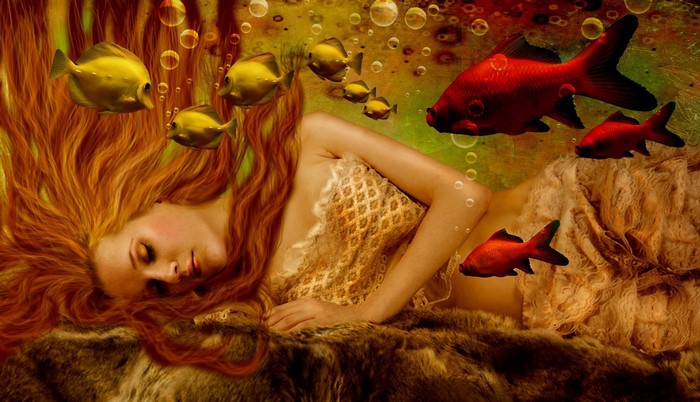 Redhead girl sleeping underwater with fish