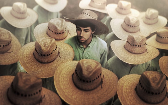 Man surrounded by men wearing straw hats
