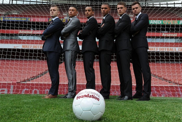 Arsenal players in suits with a football
