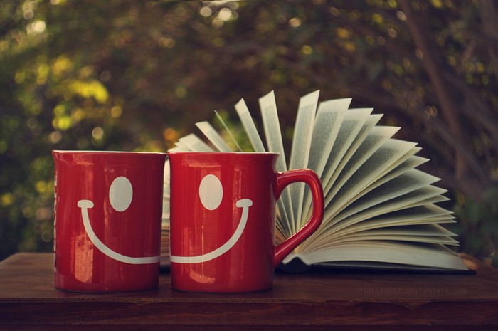 Two smiley face mugs and an open book