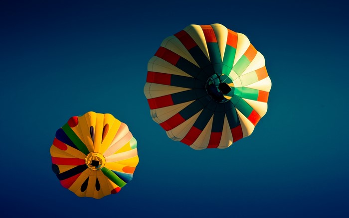 Two colorful hot air balloons against a blue sky