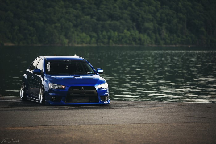 Blue Mitsubishi Lancer Evolution parked by a lake