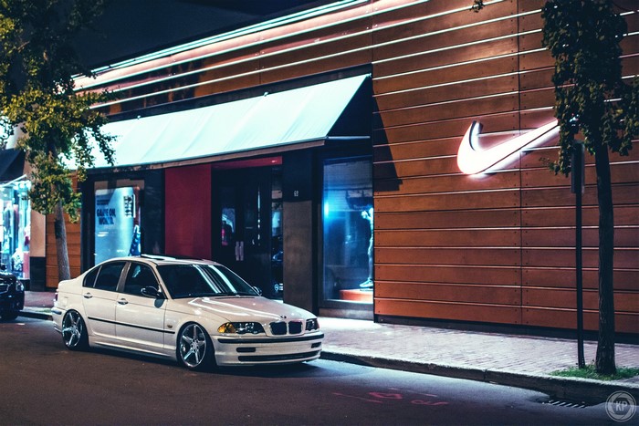 White BMW E46 parked outside Nike store at night