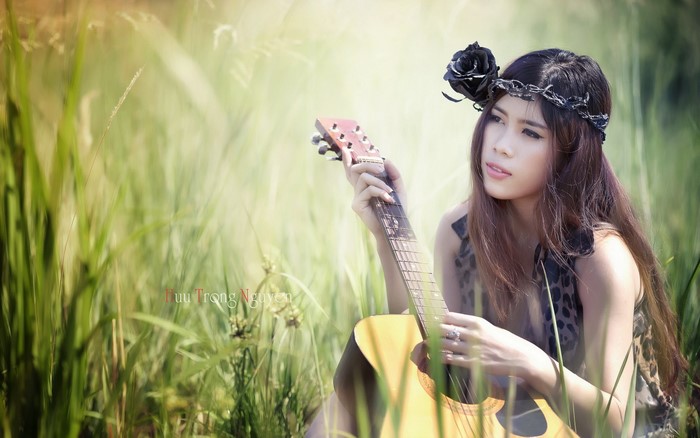 Asian woman with guitar in grass