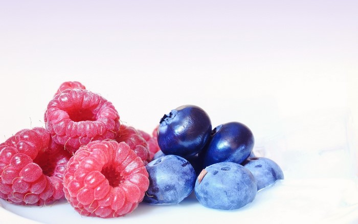 Raspberries and blueberries on a white surface