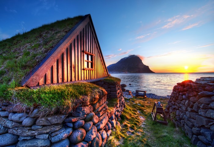 Grass-roofed house by the sea at sunset