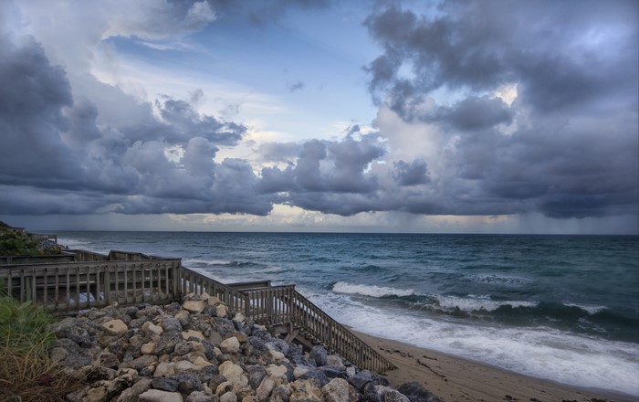 Wooden stairs leading to a stormy beach with dark clouds