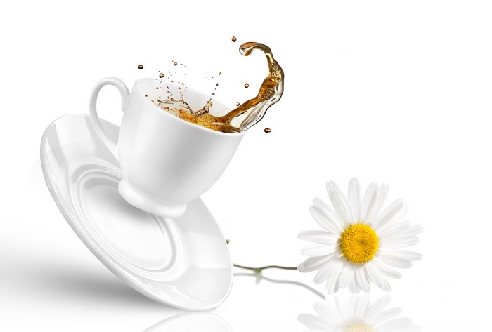 Tea splashing from a cup and saucer with a chamomile flower
