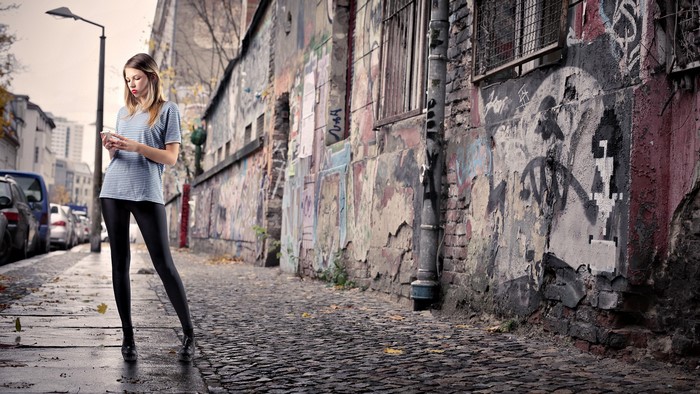 Woman in leggings looking at phone on graffiti street